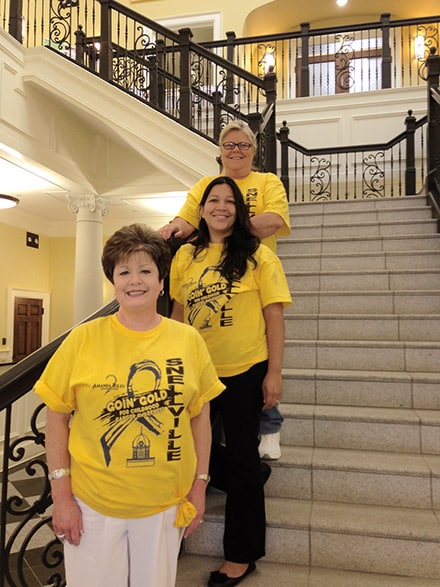 City of Snellville Staff Gloria Crosswell, Gaby Downs, and Candace Pulliam in their gold t-shirts in recognition of Amanda Riley and Childhood Cancer