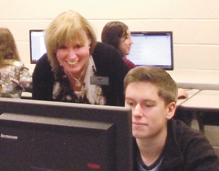 Brookwood High Spanish teacher Mary Meyer helps her students set up as they get ready to take the National Spanish Language Exam in a Brookwood High computer lab.