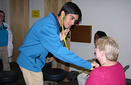 Medical Explorer Kush Patel uses a stethoscope to listen to leader Vicki Winkles' heart.