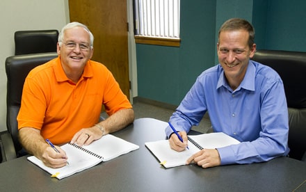 Walton EMC CEO Ronnie Lee, left, signs the construction contract for Walton EMC's new community solar project with Radiance Solar COO Jamie Porges. The project is the largest of its type in the Eastern U.S. and will allow the cooperative's customer-owners to lease a portion of the facility and receive an offset on their electric bill for the solar electricity generated.
