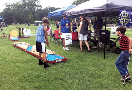 Rotarians look on as a young man plays the “Grand Canyon” mini-golf hole during the Rotary Club of Lawrenceville’s Par-Tee in the Park at ArtsFest Gwinnett.