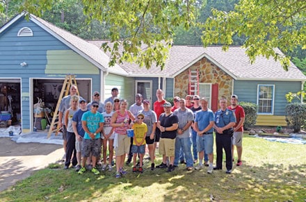 Volunteers from the police academy work to repair a local home