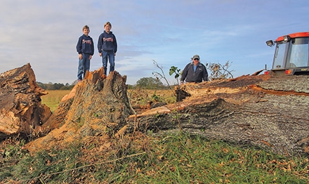 Chad Alexander Smith’s sons, Clay Smith (left) and Rett Smith (right) standing on the large trunk with their grandfather Don Smith on the right.  