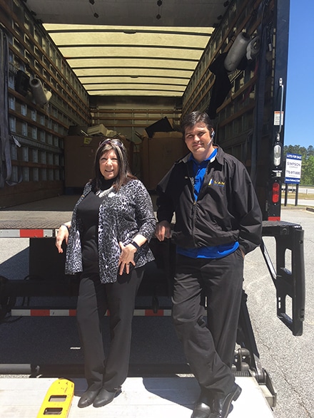 (L-R) Hester and Brooks stop to pose as items for recycling are loaded onto a truck. Hester was “thrilled” to see how many Items LAN Systems collected at this year’s Earth Day recycling event.