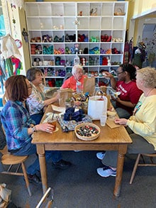 Sitting around her table, the women work on their respective projects, and as Carol jokes, "Come up with solutions to the world's problems." L-R: Sharon Murphy, Jody Berg, Carol Sigrist, Chloe Combs and Jennifer Little.