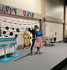 Thespians from the Buford High School performing a partner dance for the audience at 1950s-themed fashion show.