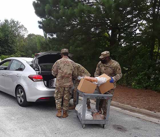 The National Guard helps out the SE Gwinnett Co-op by loading boxes of food into the cars