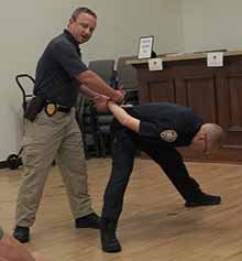 Sgt. Rob Kirschner, left, demonstrates the correct way to handcuff a suspect so he cannot free himself from the officer’s grip, as Lt. Tim Allen acts the part of the perpetrator.