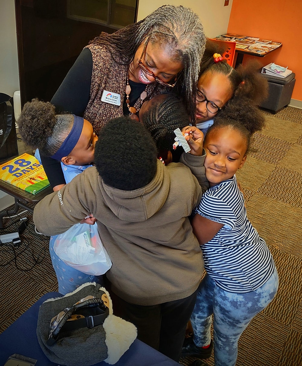 Rainbow Village CEO Melanie Conner getting a group hug from some her nonprofits youngest residents.